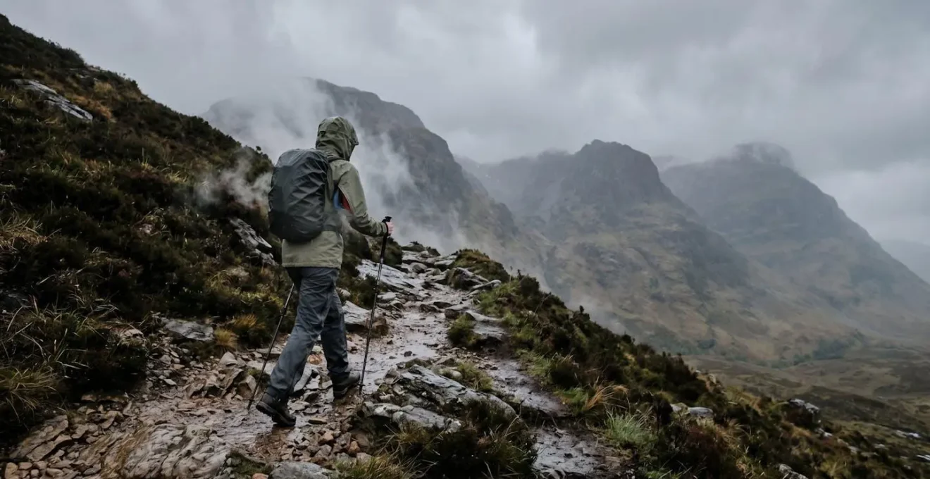 Randonneur en montagne gérant la ventilation de sa veste imperméable sous la pluie