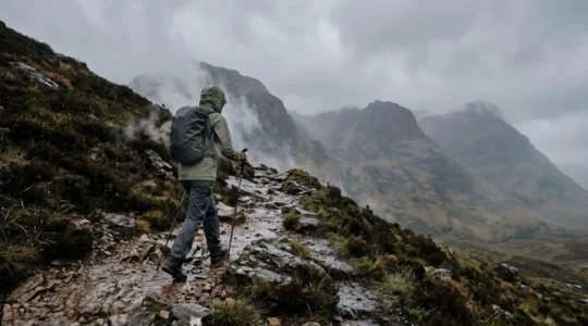 Randonneur en montagne gérant la ventilation de sa veste imperméable sous la pluie