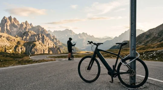Cycliste en voyage avec son vélo à assistance électrique sécurisé devant un paysage montagneux